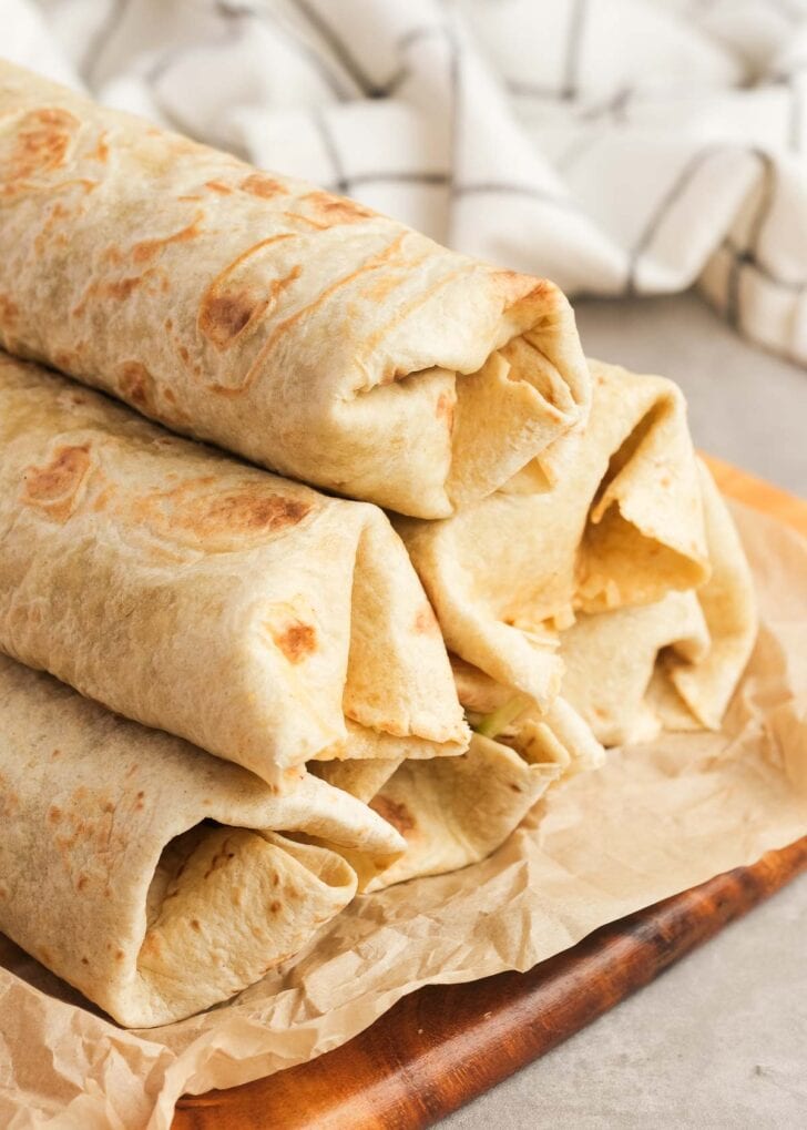 six big mac wraps rolled up and stacked on a cutting board