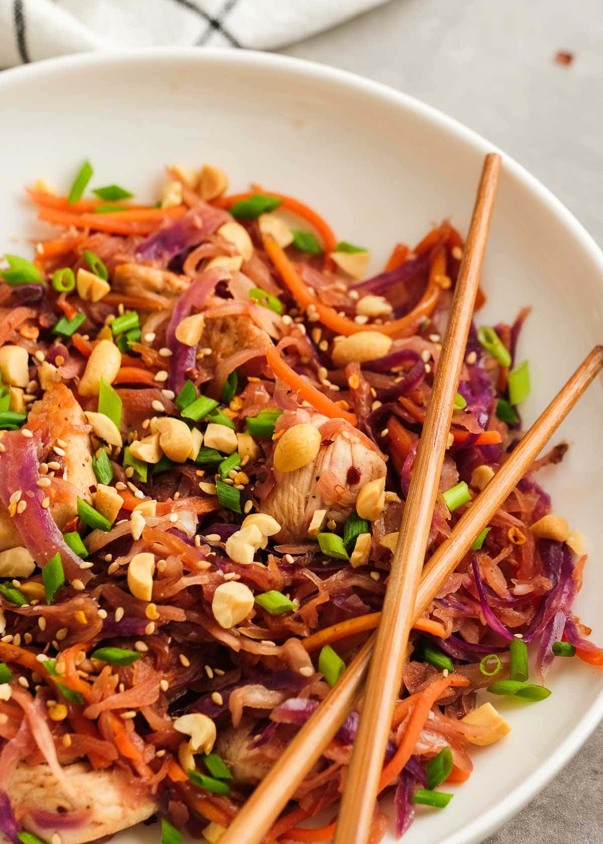 two chopsticks over a white dish loaded with colorful chicken egg roll in a bowl