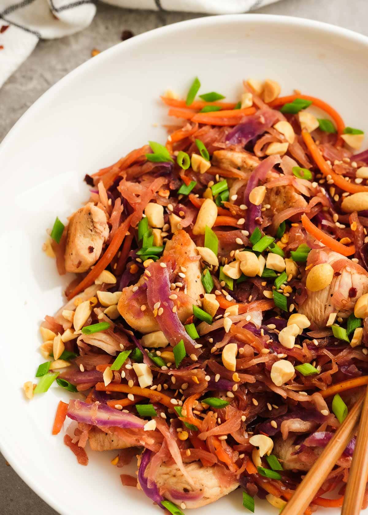 closeup view showing crunchy garnishes on chicken egg roll in a bowl on a white plate