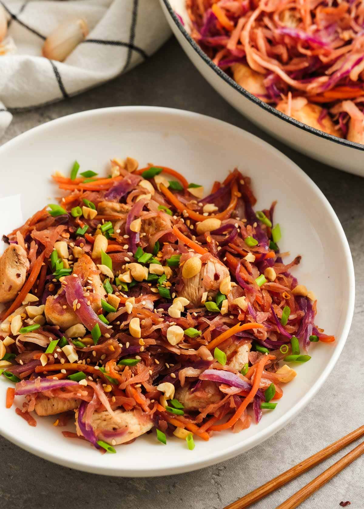 a white bowl of chicken egg roll in a bowl beside a large pot full of the keto dinner