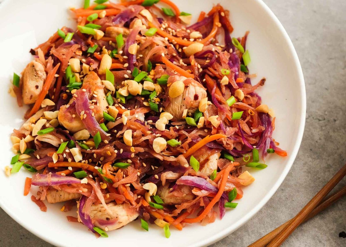 horizontal image showing a white shallow bowl filled with colorful chicken egg roll in a bowl