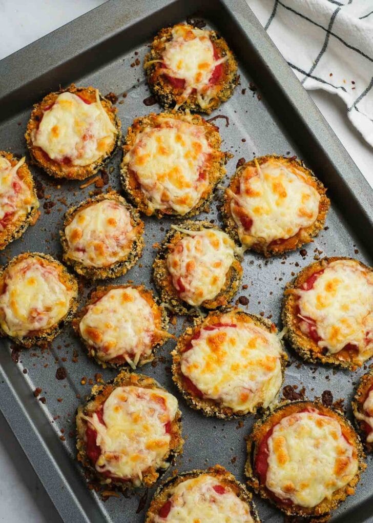 melty cheese baked until golden brown on top of crispy eggplant rounds with marinara sauce on a baking sheet