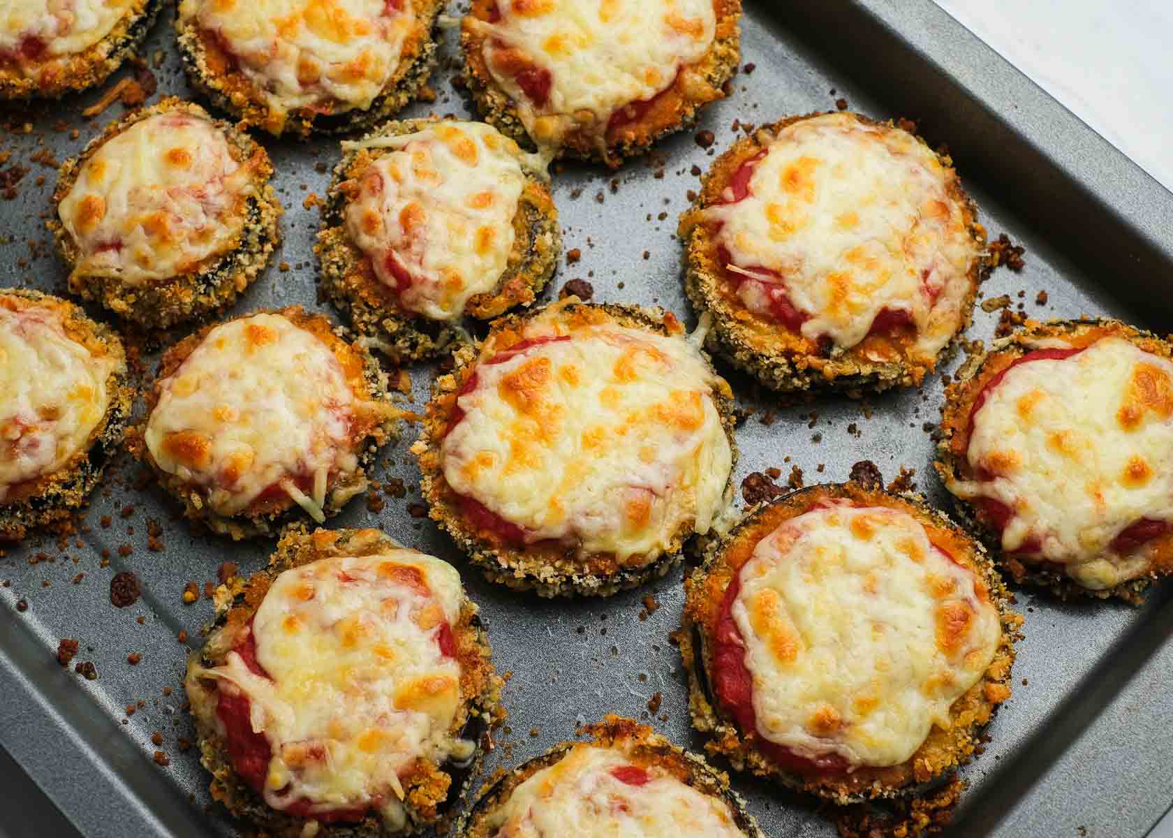 crispy eggplant bites topped with marinara and shredded mozzarella, baked until golden brown on a pan