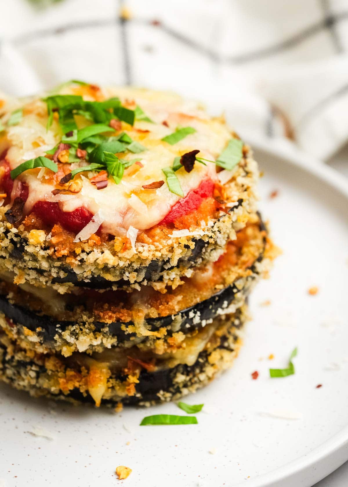 closeup shot of eggplant mozzarella stacks with crispy breading, creamy mozzarella, and melty cheese with fresh herbs