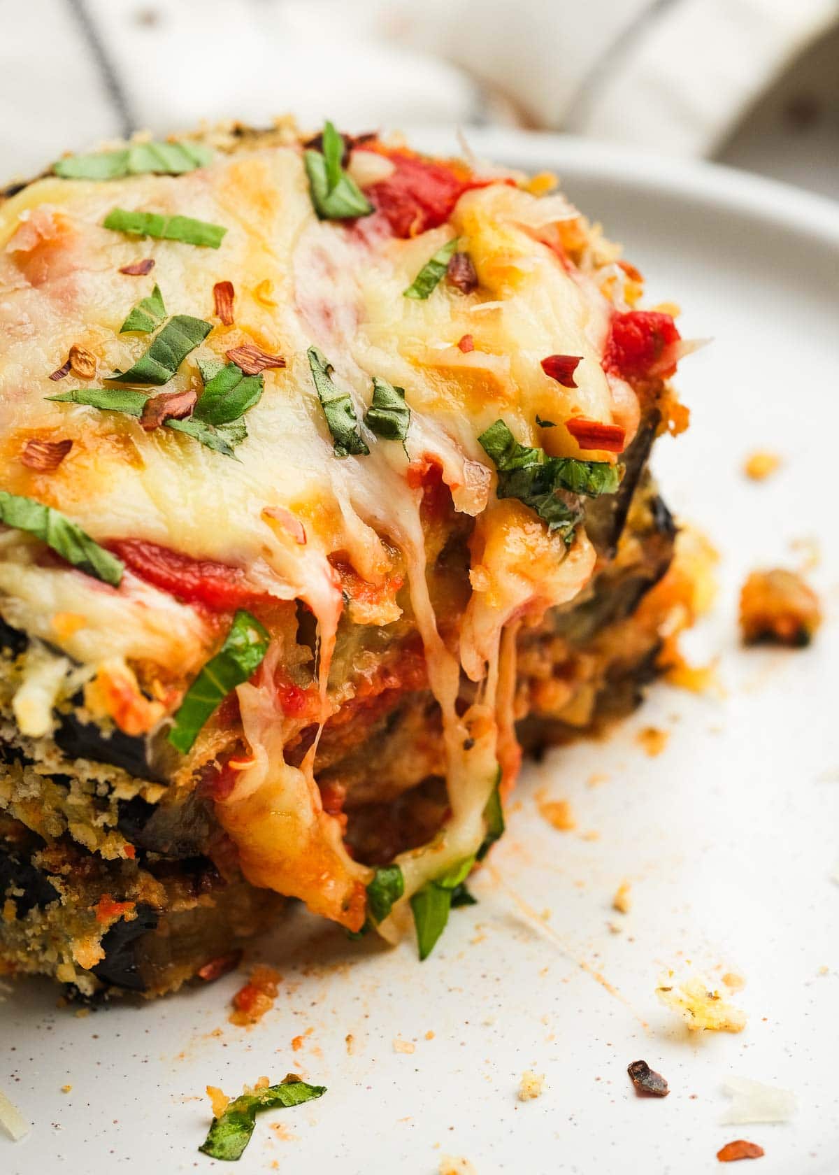 A stack of three eggplant parmesan bites sliced with gooey, melty cheese