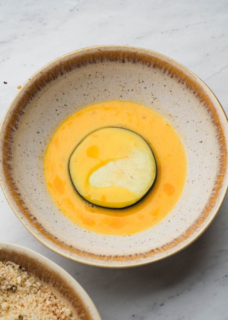 eggplant slice in an egg bath in a bowl