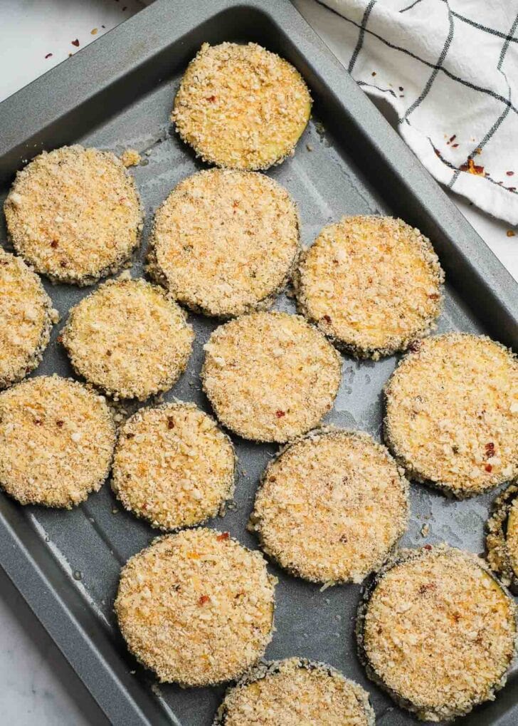 breaded eggplant slices on a lightly greased baking sheet