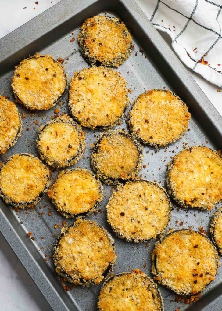 perfectly tender eggplant slices with a crispy breading on a baking pan