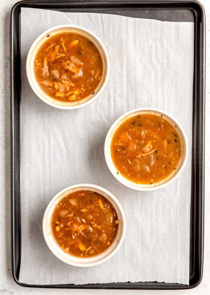 ramekins full of french onion chicken soup on a baking sheet