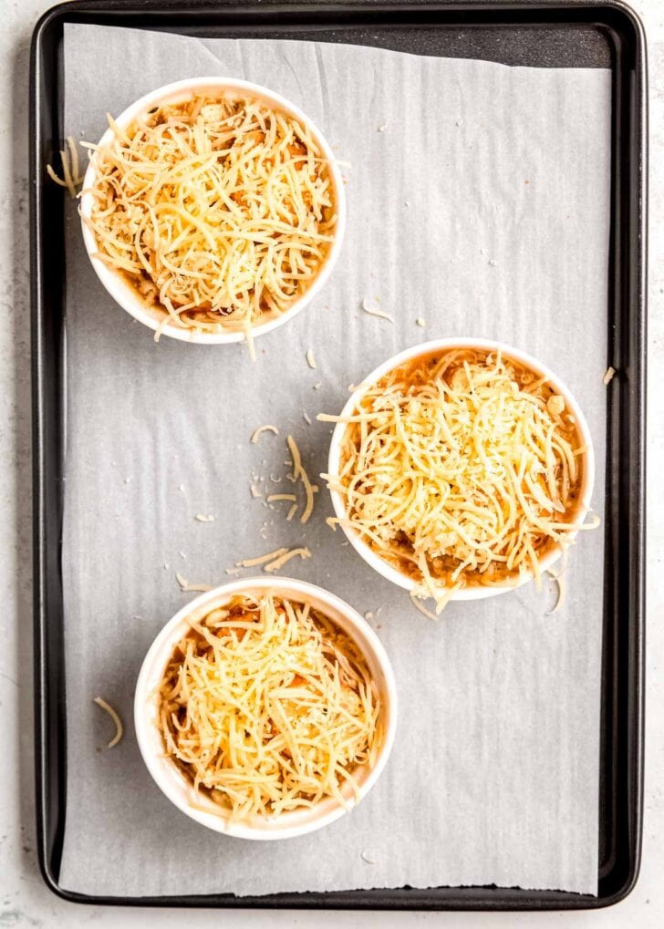 french onion chicken soup and toasted baguette slices covered with shredded gruyere cheese