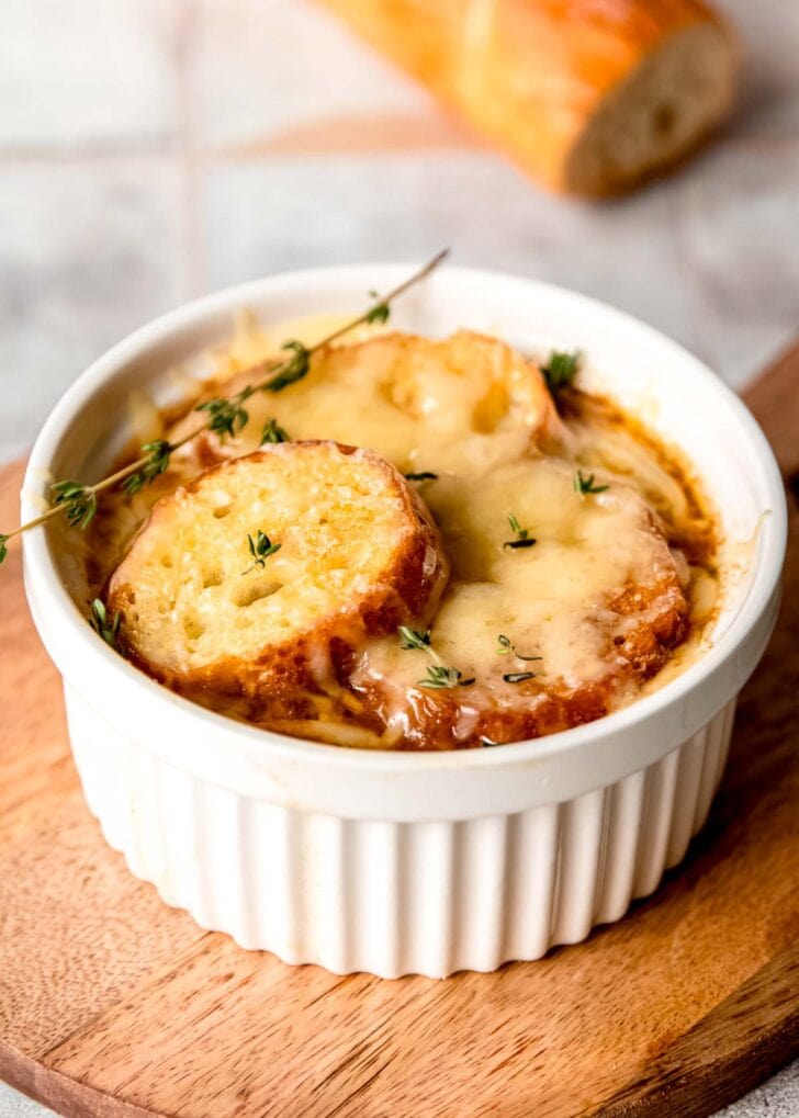 closeup view of french onion chicken soup in a ramekin on a cutting board