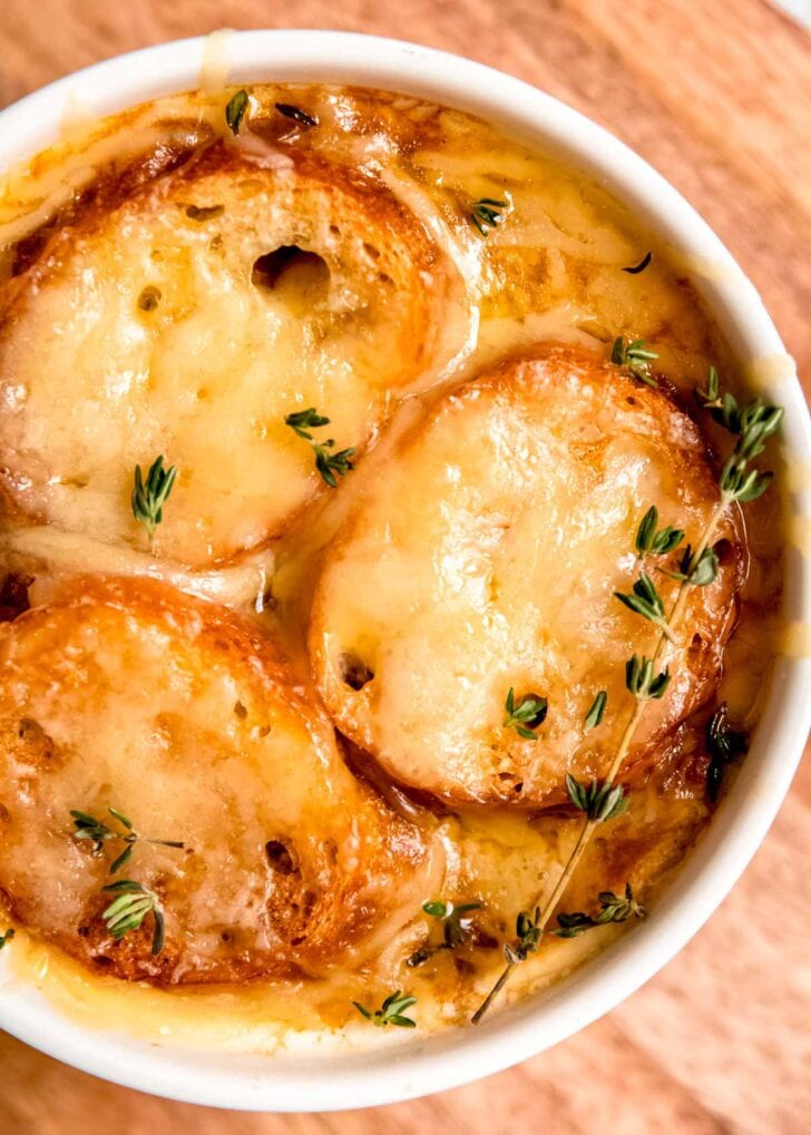 closeup overhead shot showing melty gruyere cheese over toasted baguette slices in a bowl of french onion soup with chicken