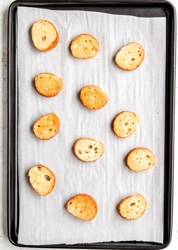 toasted french baguette on a baking sheet lined with parchment paper, ready for french onion soup