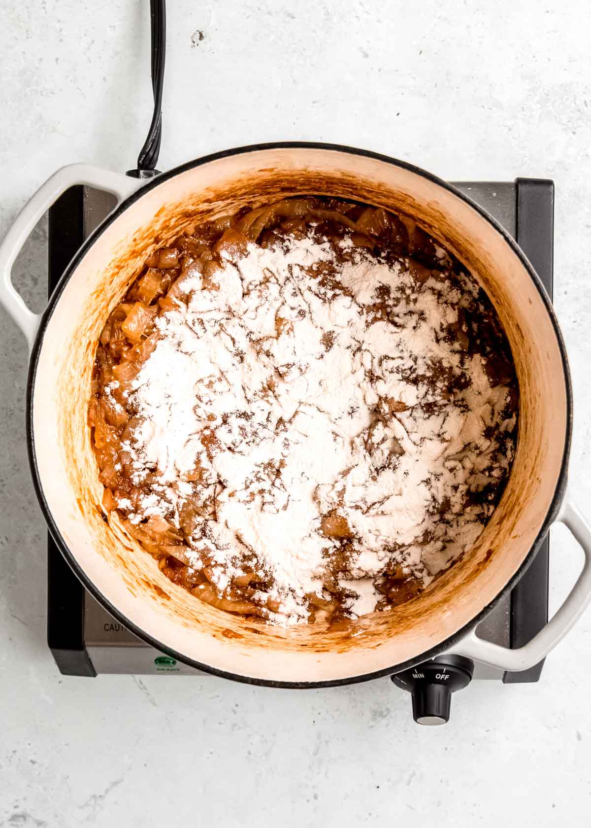 flour sprinkled over caramelized onion in a dutch oven