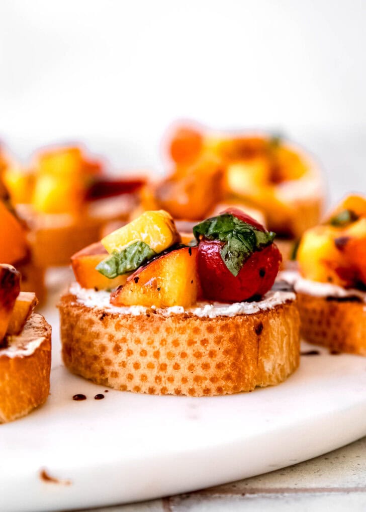 closeup view of easy bruschetta with peaches, tomatoes, basil, goat cheese, and balsamic reduction