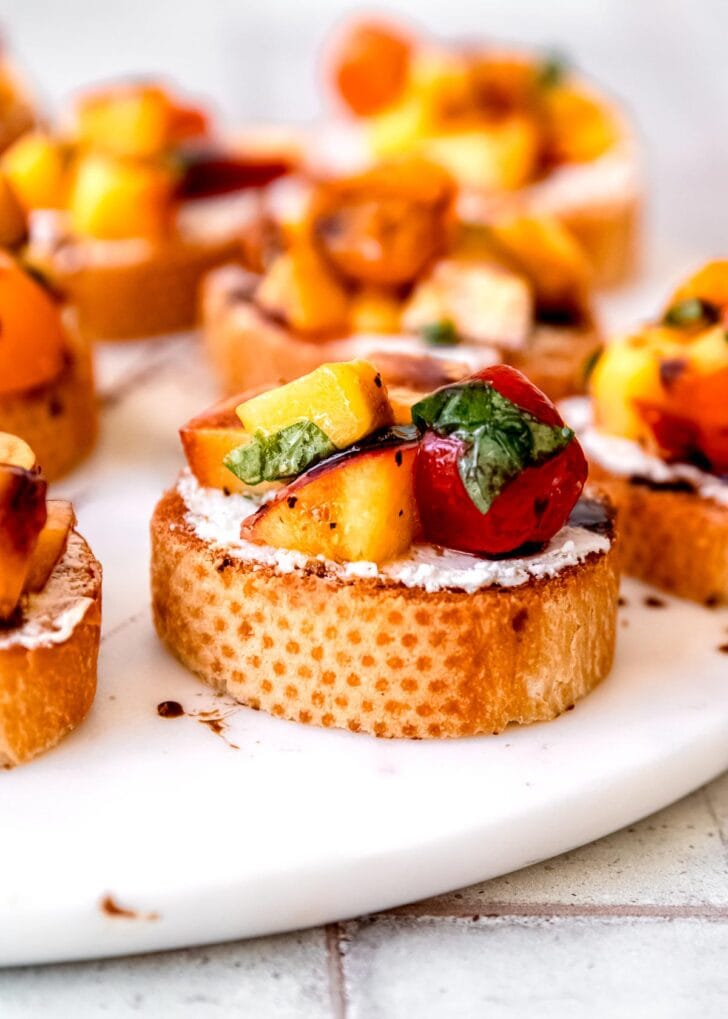 several pieces of peach bruschetta on a white platter