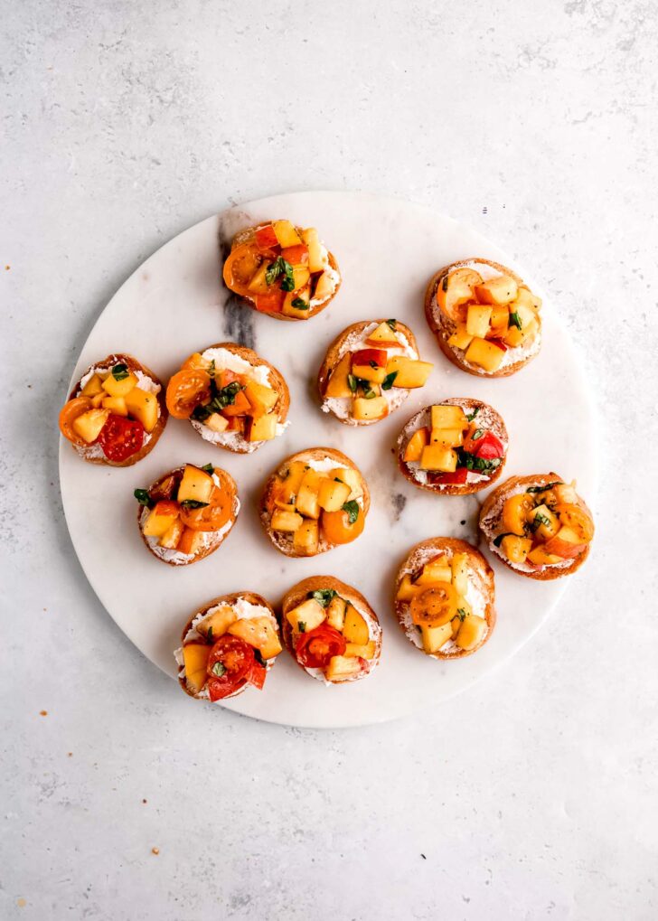 peach tomato basil mixture spooned atop goat cheese spread on toasted baguettes