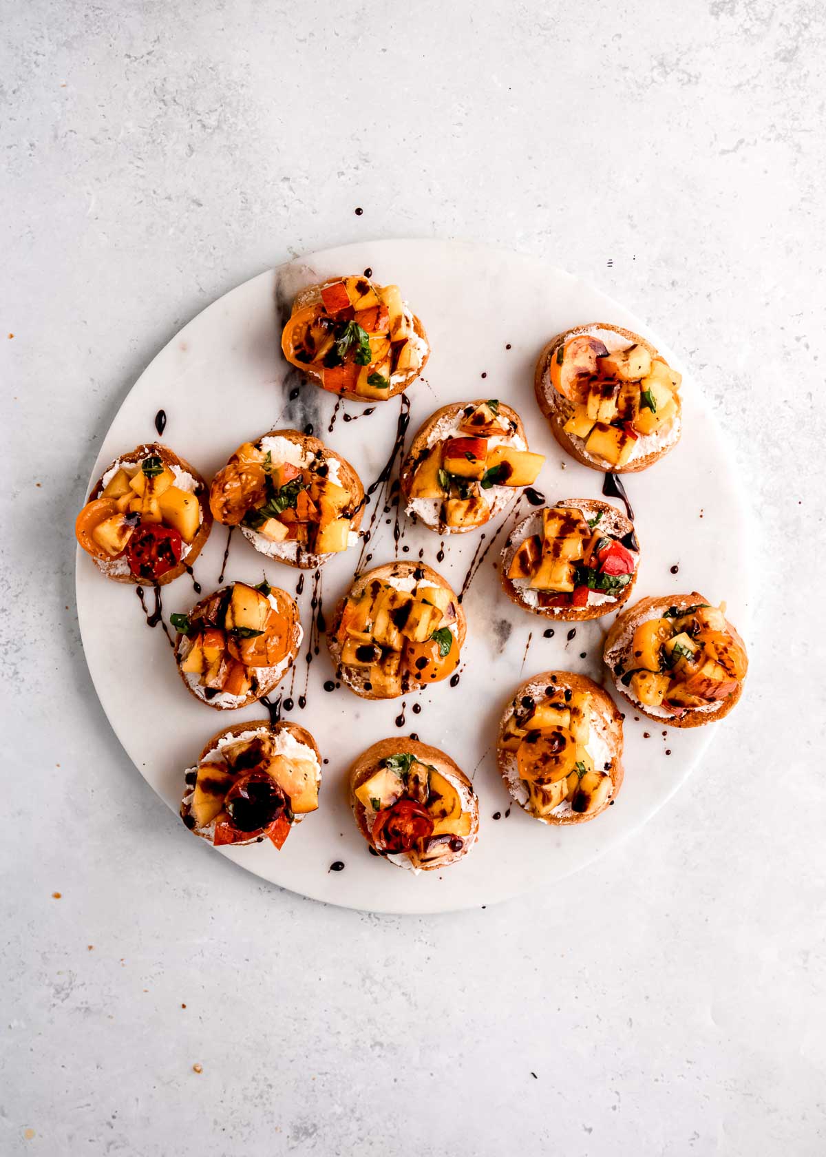 a sweet balsamic reduction drizzled over peach bruschetta on a white plate