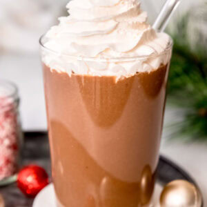 a tall glass filled with a peppermint mocha protein shake and topped with keto whipped cream