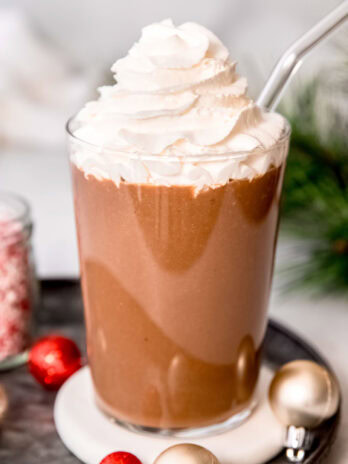 a tall glass filled with a peppermint mocha protein shake and topped with keto whipped cream