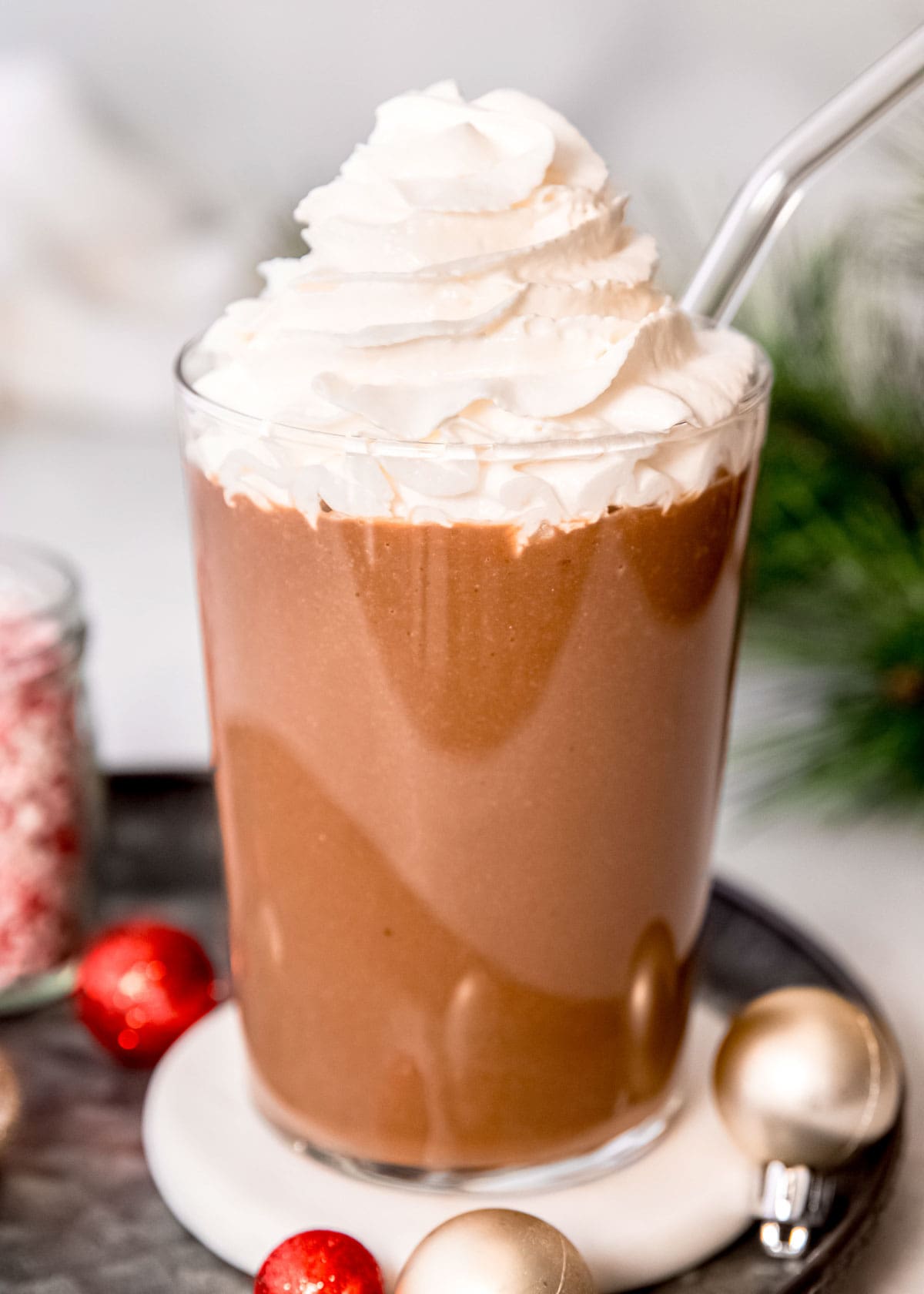 a tall glass filled with a peppermint mocha protein shake and topped with keto whipped cream