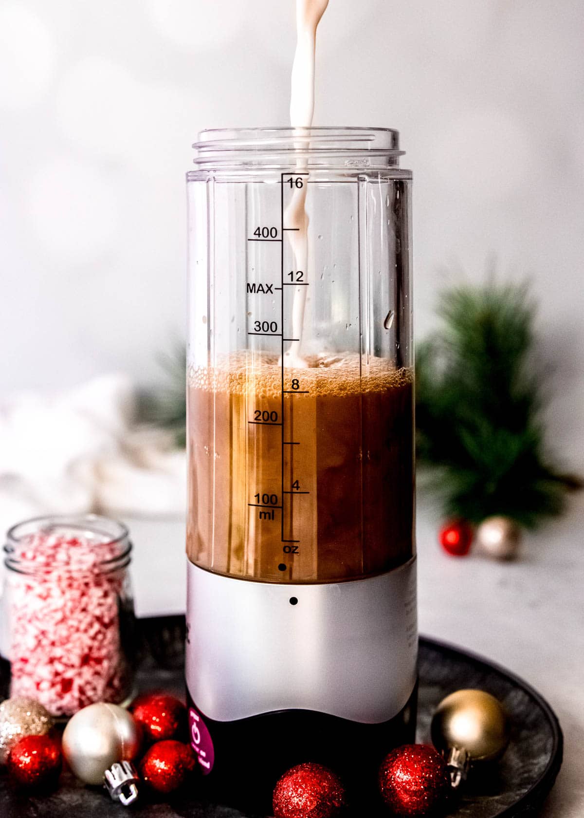 almond milk being poured into the blender with coffee for a peppermint mocha protein shake