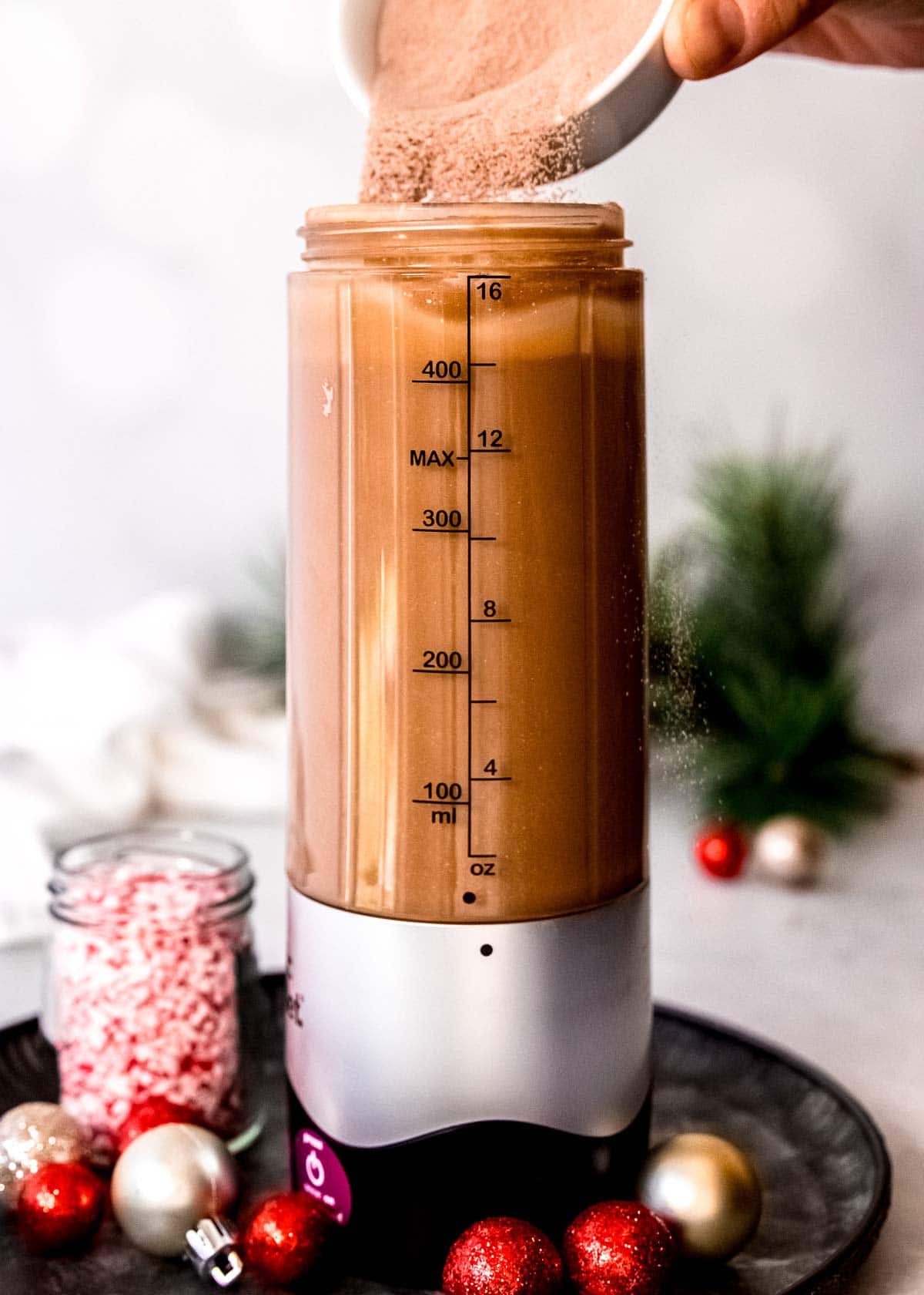 protein powder being added to a peppermint mocha shake in a blender