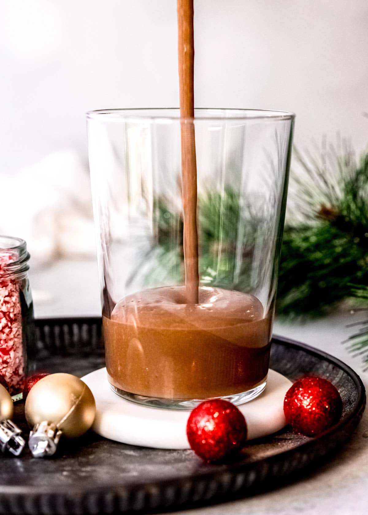 a thick peppermint mocha protein shake being poured into a tall glass