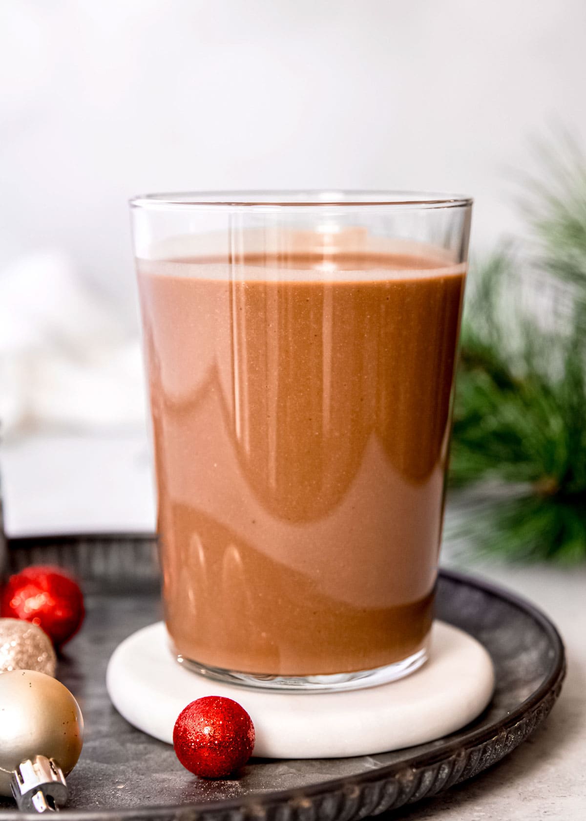 creamy peppermint mocha smoothie in a glass on a white coaster and black platter