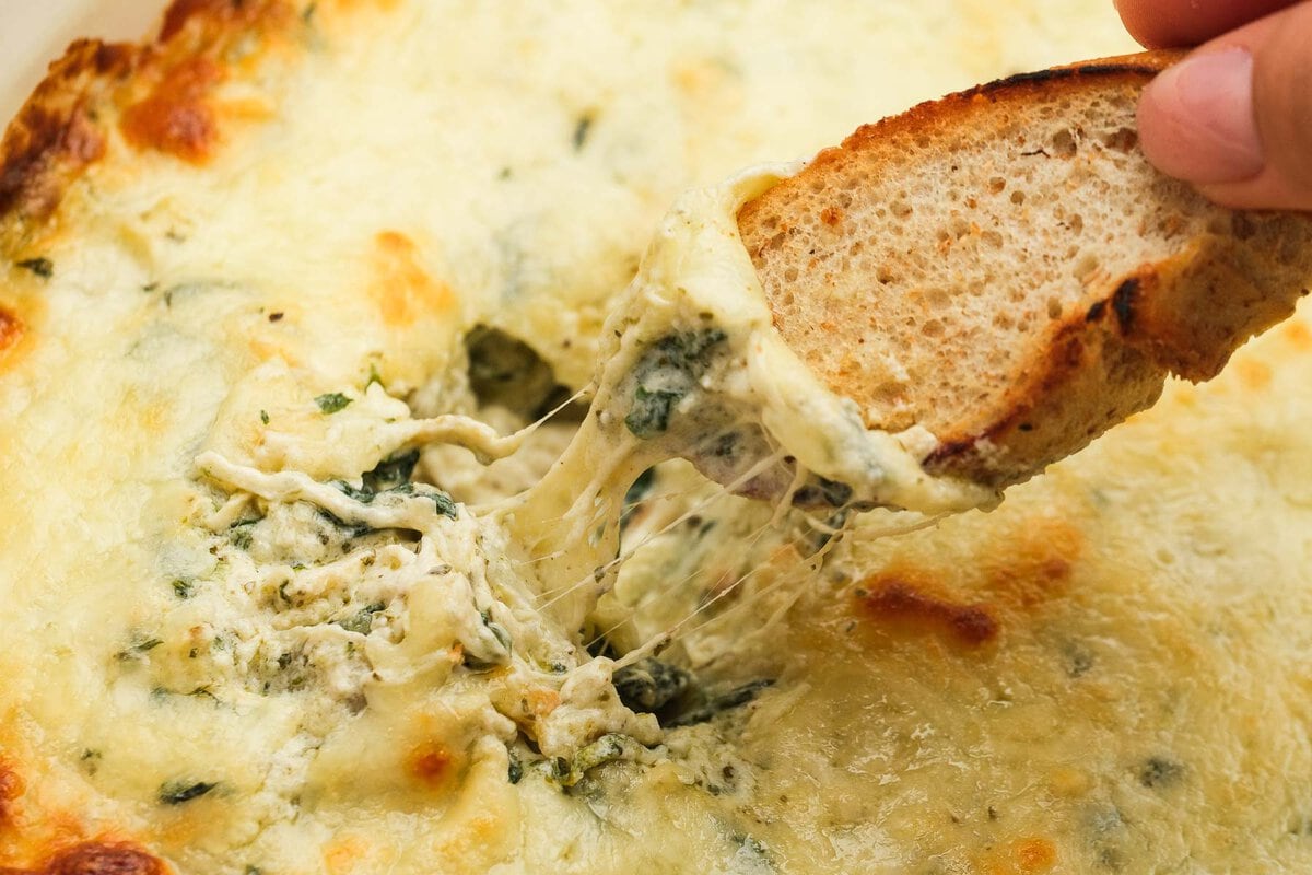 horizontal image showing the creamy, cheesy dip filled with chicken, artichokes, and spinach