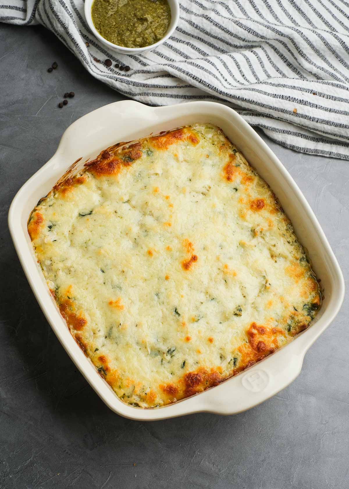 the perfect pesto chicken dip baked until golden brown at the edges with a hot and bubbly center