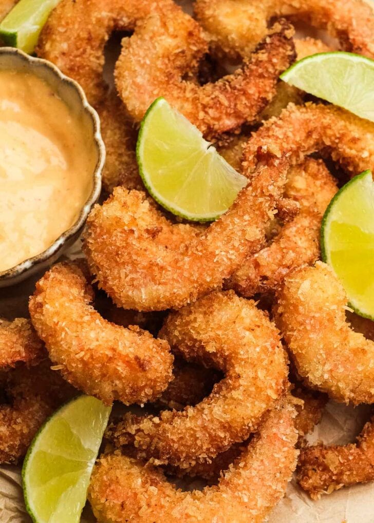 closeup of crispy gluten-free breading on easy popcorn shrimp with limes and a mayo-chili dipping sauce