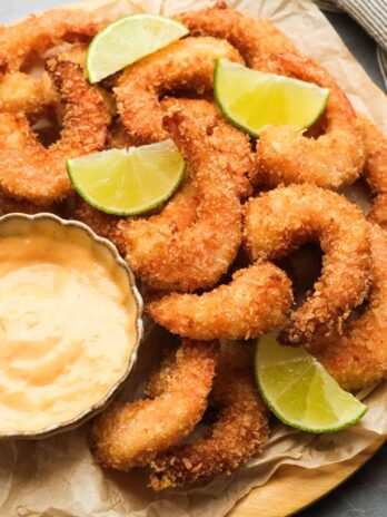 crispy, crunchy, gluten-free popcorn shrimp piled high with lime wedges and a side of dipping sauce