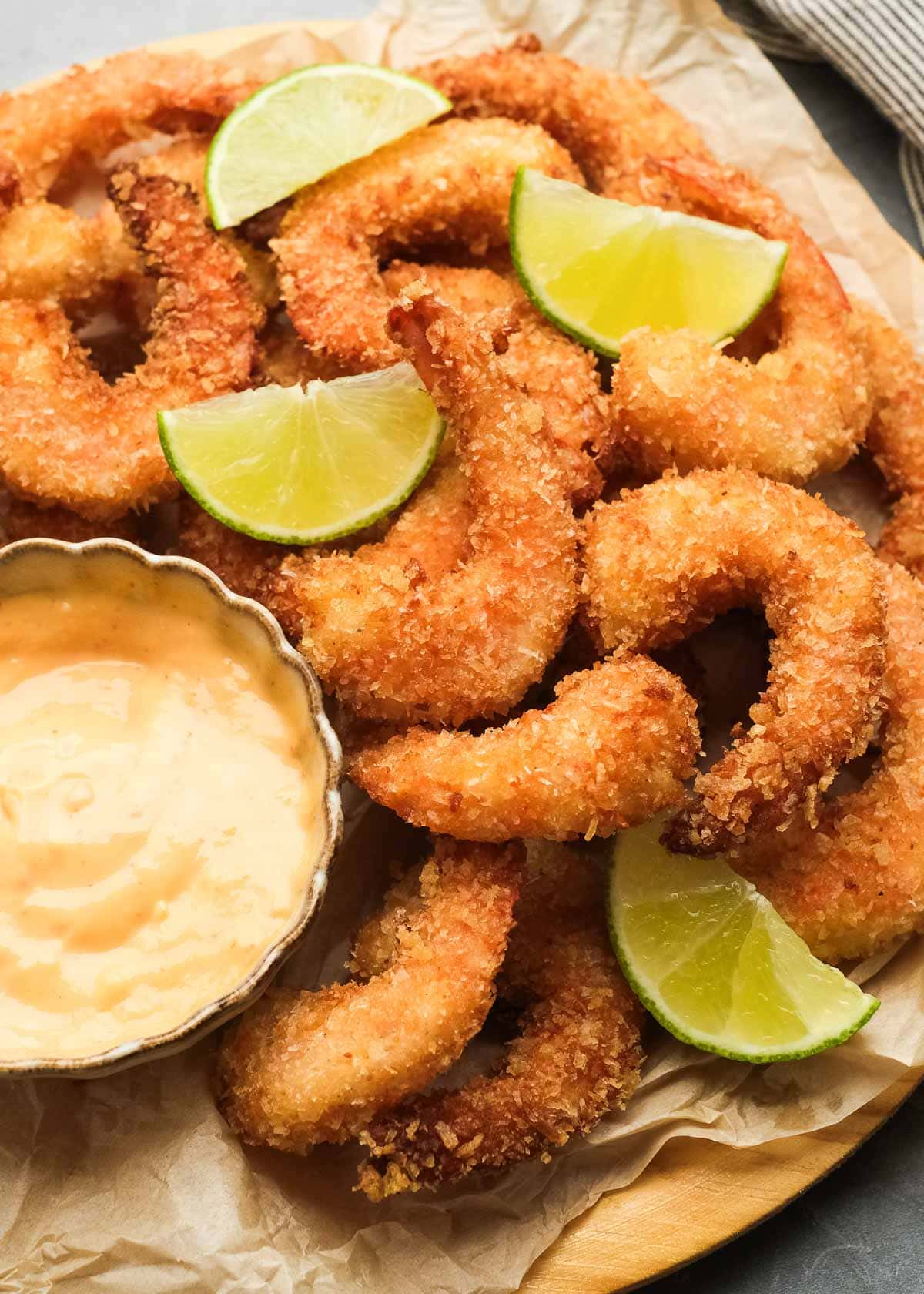 crispy, crunchy, gluten-free popcorn shrimp piled high with lime wedges and a side of dipping sauce