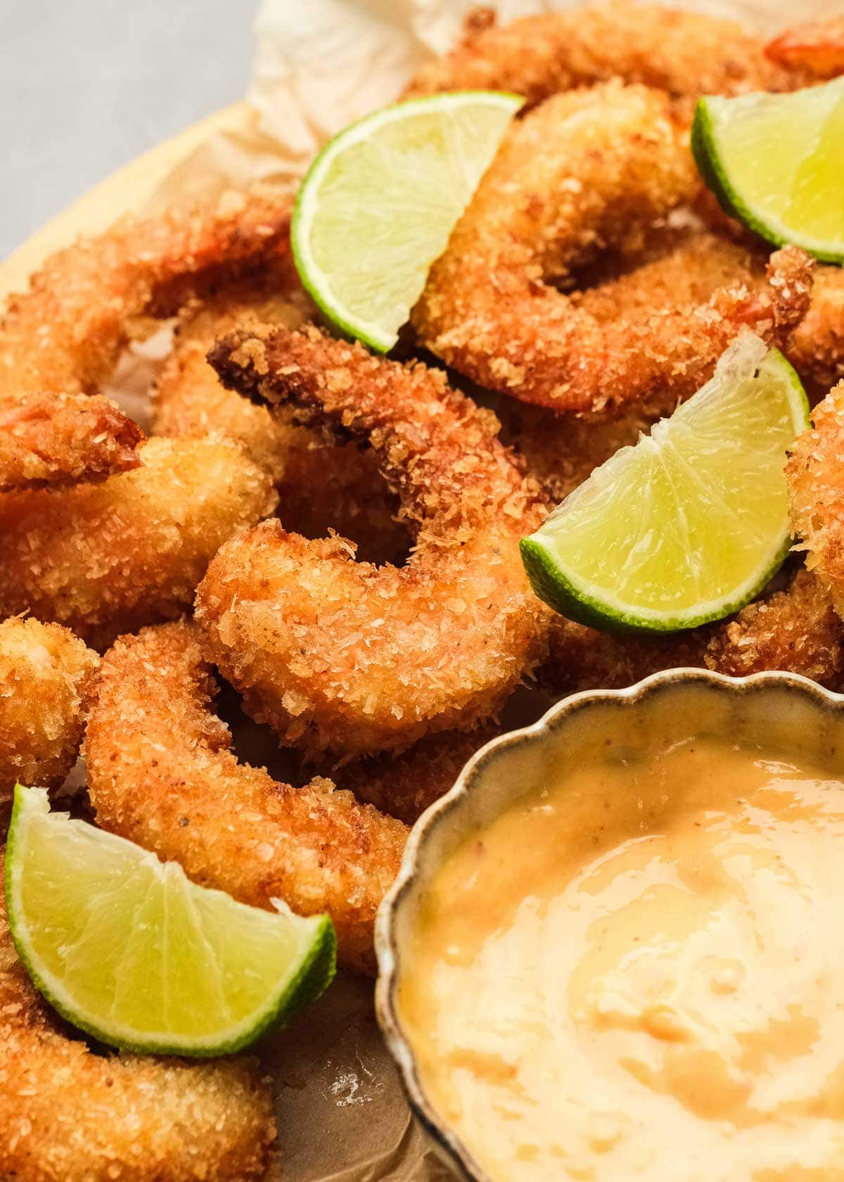 closeup showing crunchy popcorn shrimp with lime wedges and a side of dipping sauce