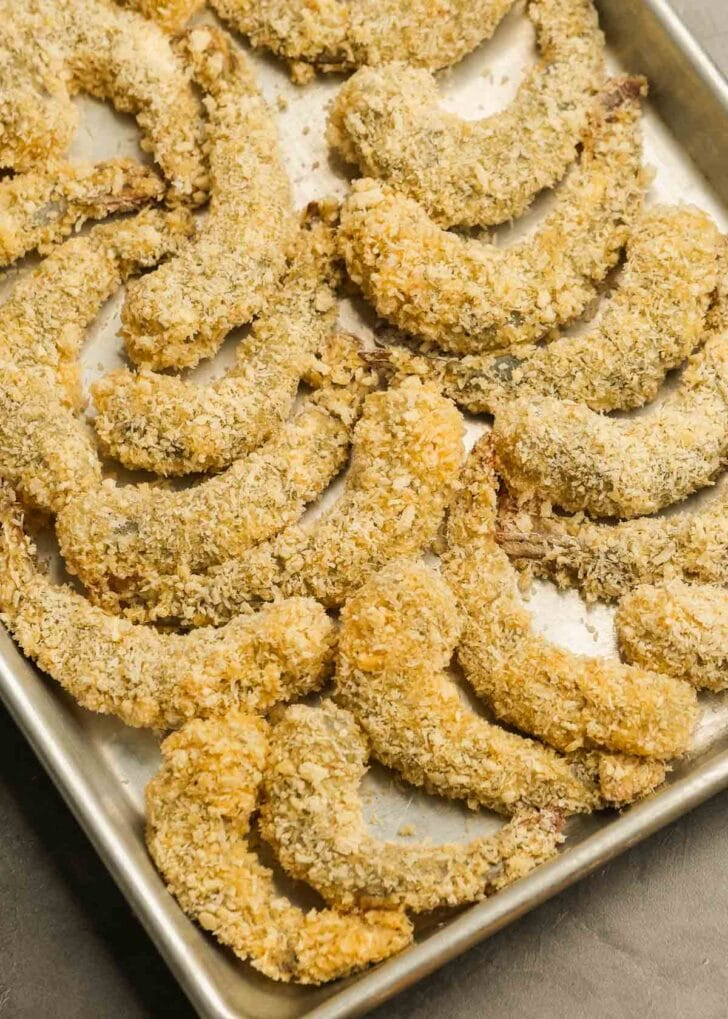 breaded shrimp on a baking sheet waiting to be fried