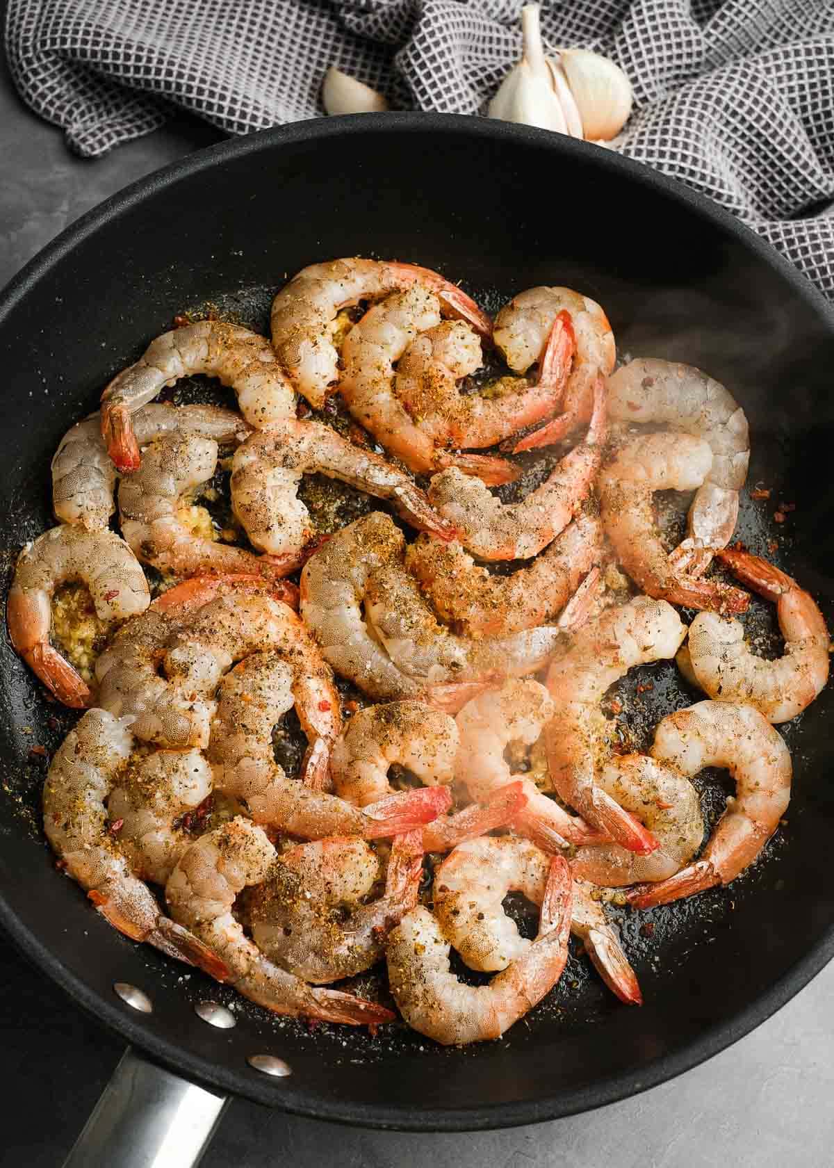 Shrimp cooking in a single layer in a skillet with olive oil and butter