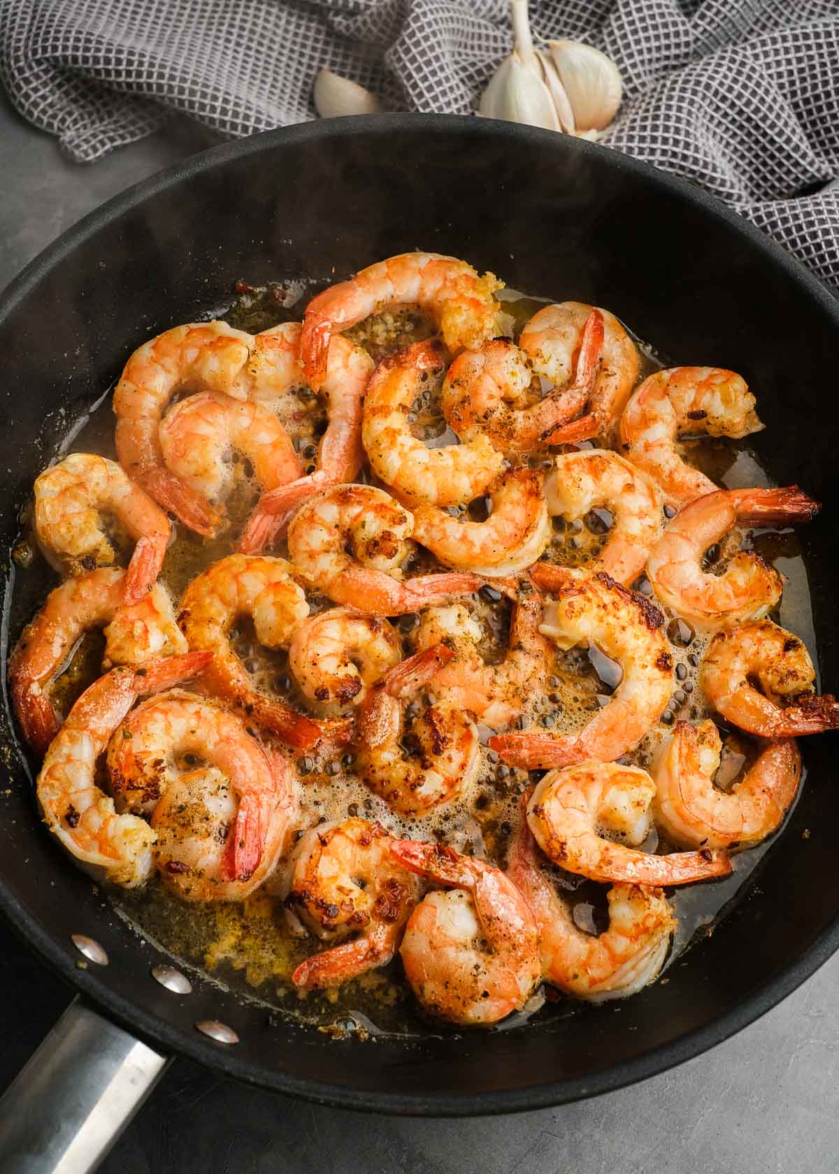 shrimp scampi cooking in a garlicky butter sauce in a black skillet