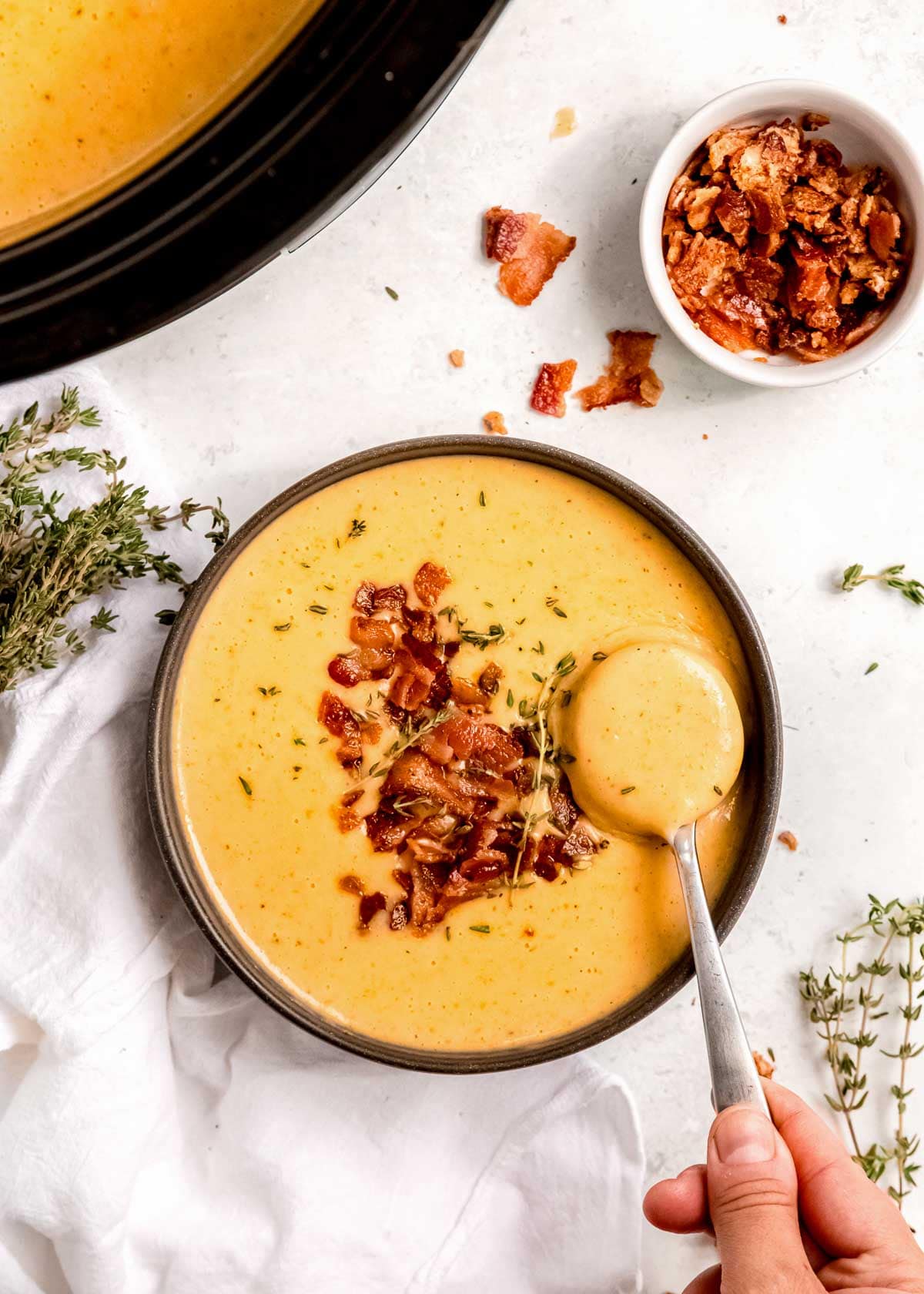 creamy potato soup in a black bowl with a side of cooked bacon