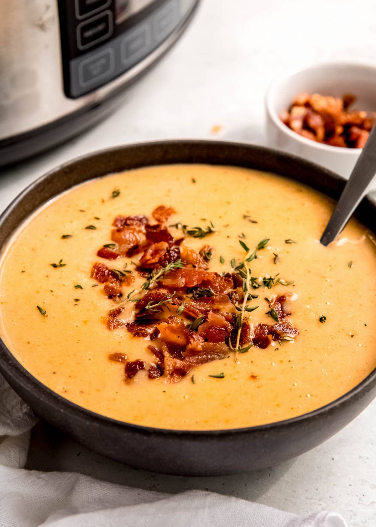 a black bowl full of cheesy potato soup with bacon on top