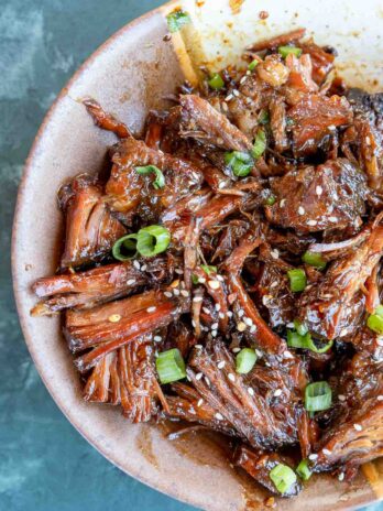 closeup view of juicy sweet and spicy slow cooker beef, shredded and covered with asian inspired sauce