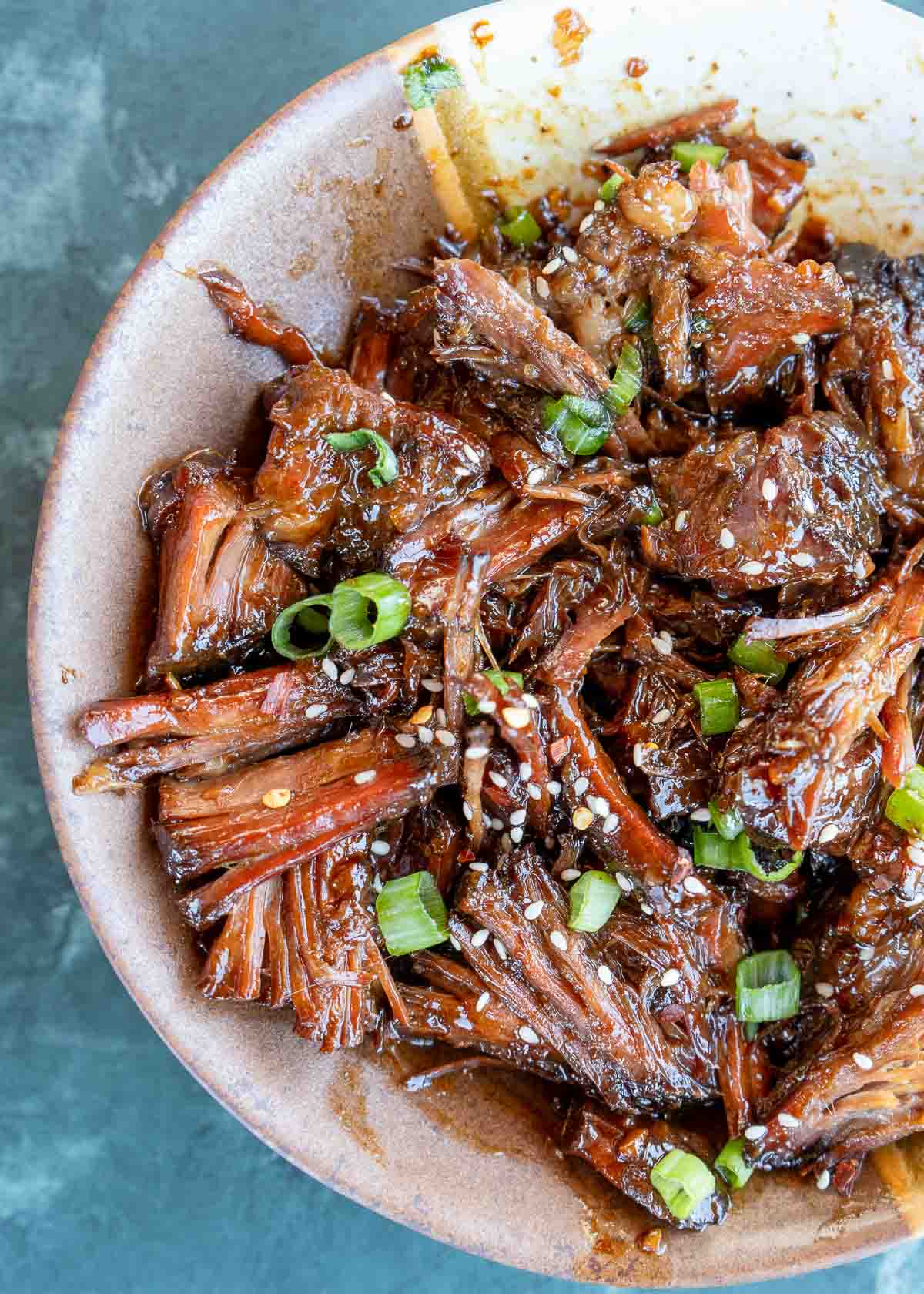 closeup view of juicy sweet and spicy slow cooker beef, shredded and covered with asian inspired sauce