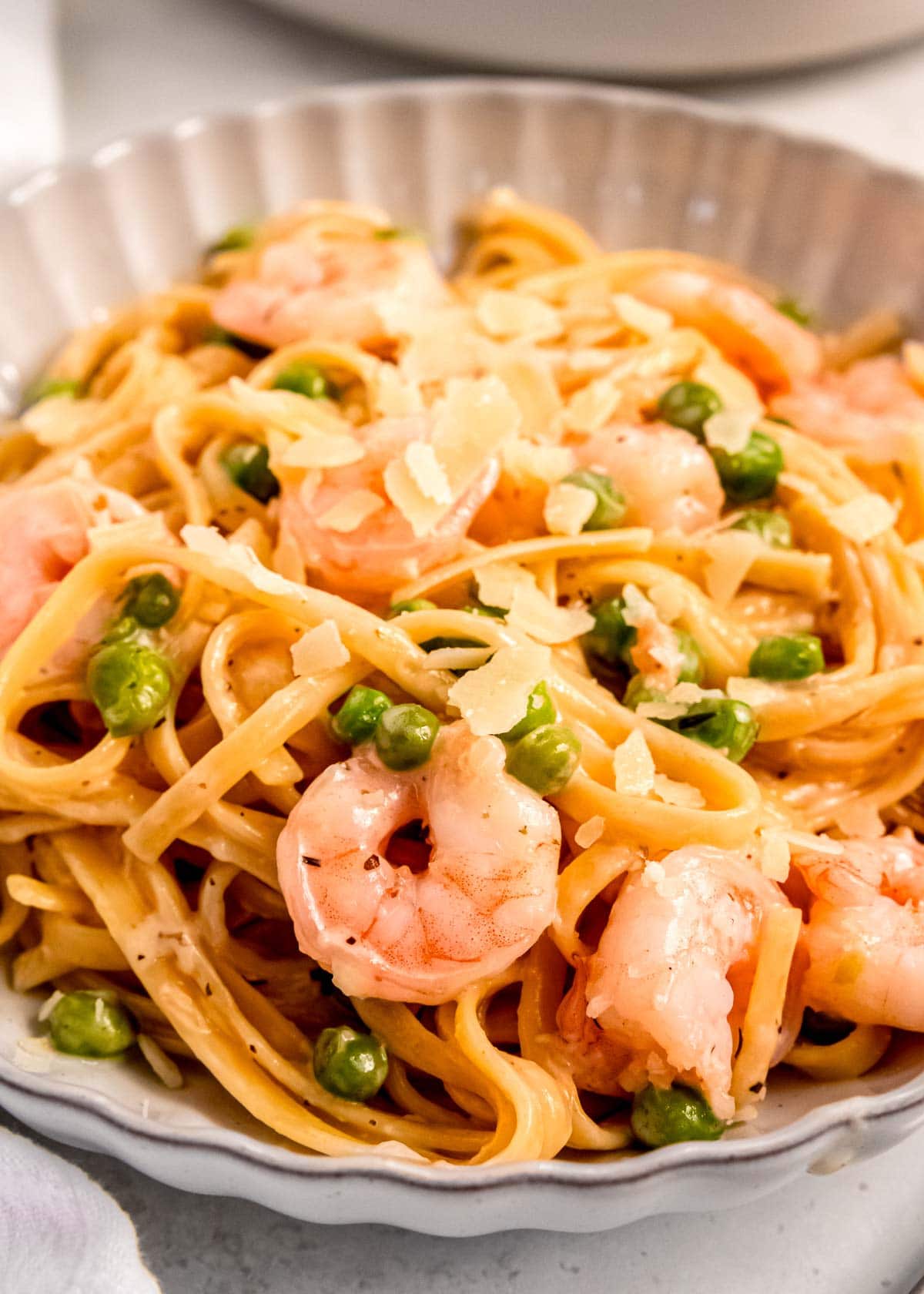 side angle showing juicy shrimp and healthy peas in a creamy, lemony sauce coating linguine noodles