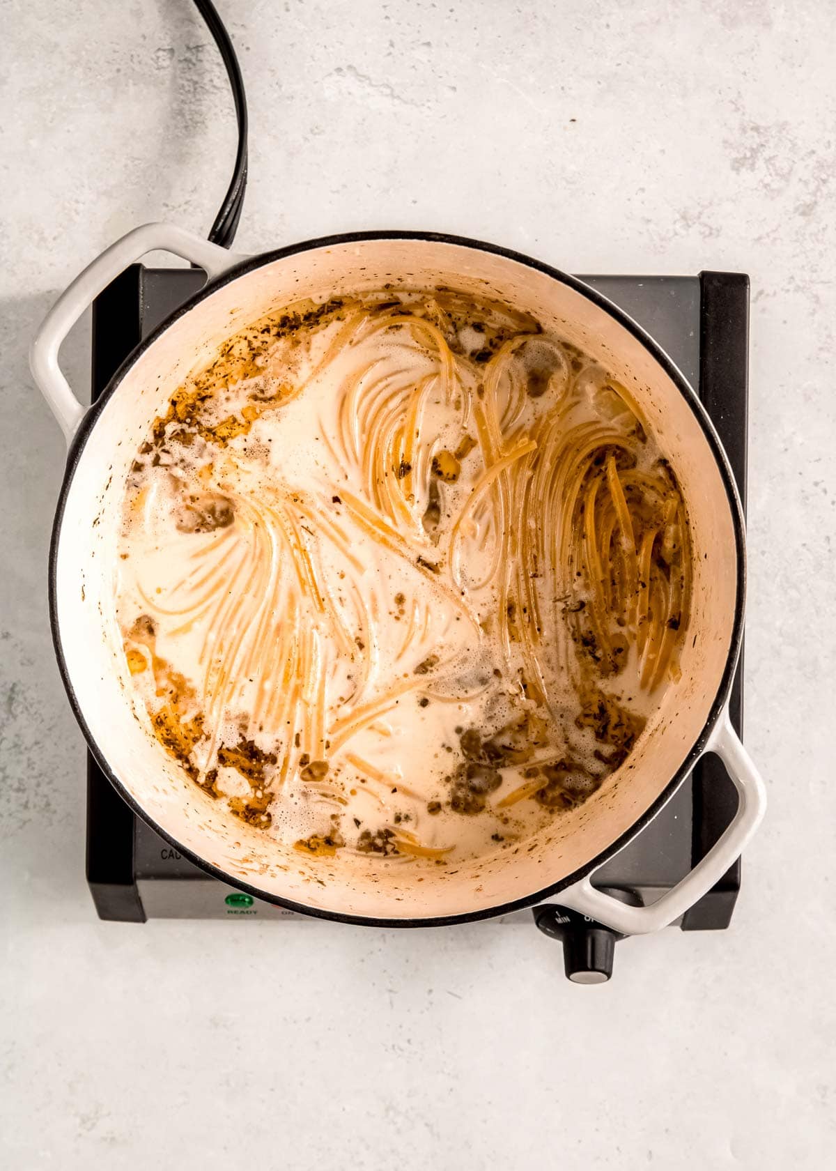 linguine noodles boiling in seasoned broth and heavy cream