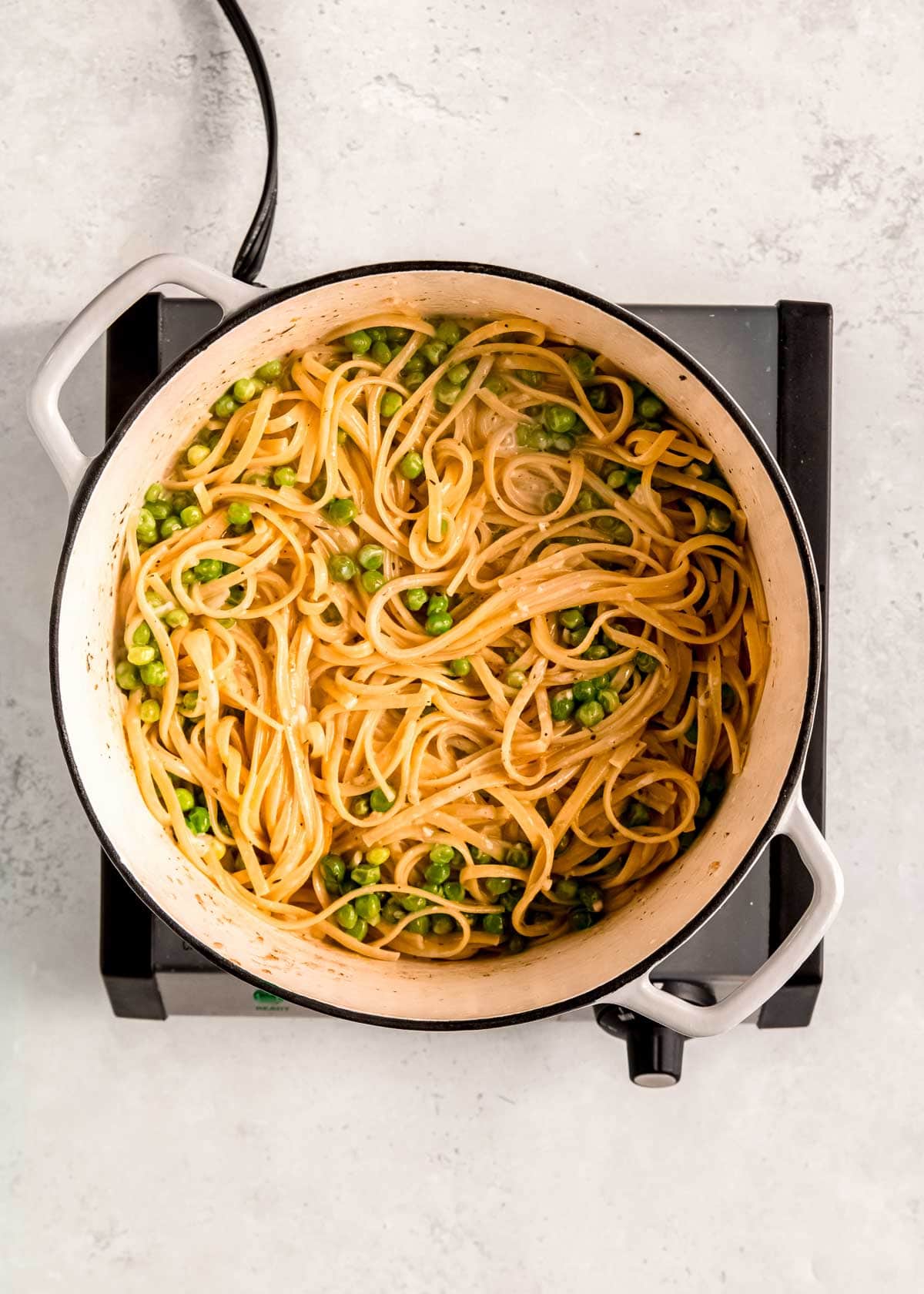 cooked linguine, peas, onions, and garlic in a creamy sauce in a dutch oven