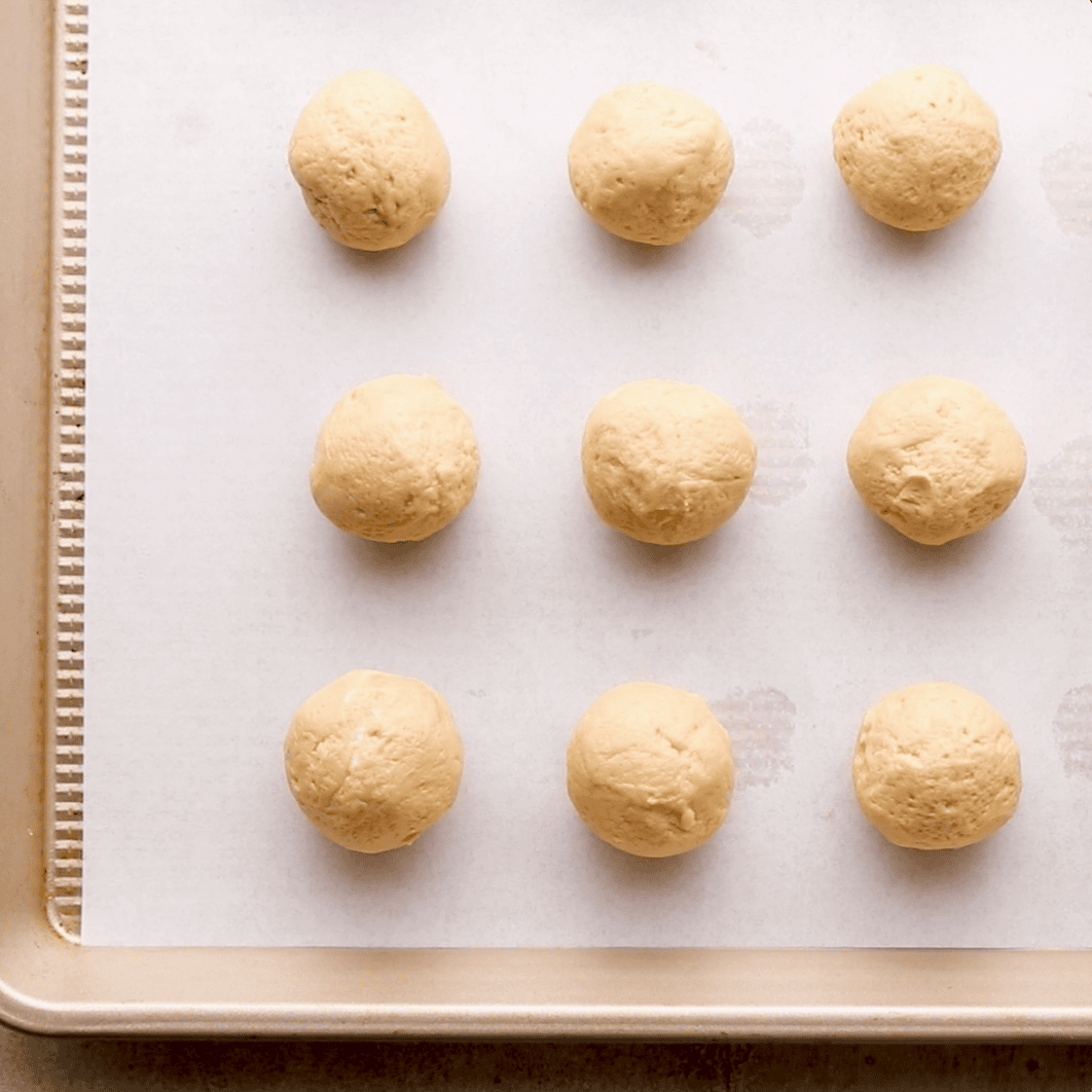 peanut butter cheesecake truffle filling rolled into balls on baking sheet