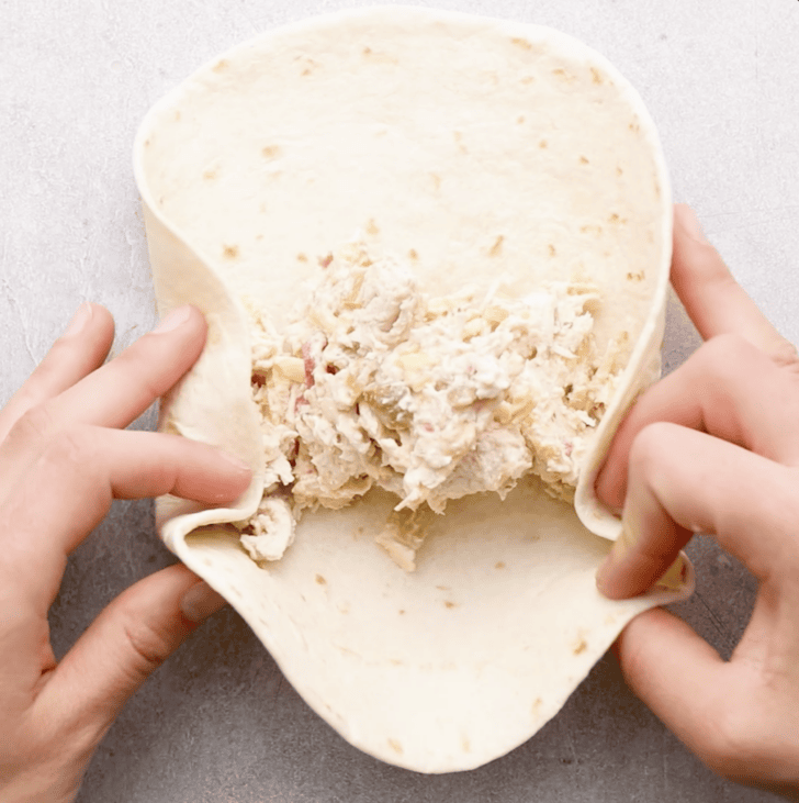 chicken mixed being folded into chimichangas