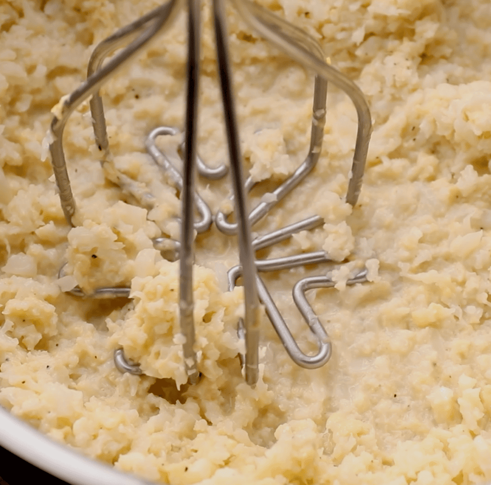 cauliflower being mashed in skillet