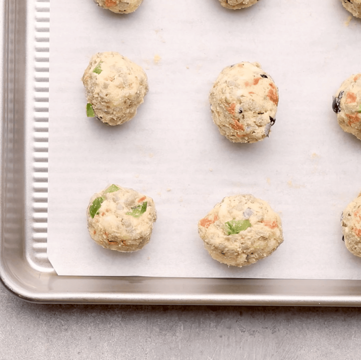 raw pizza puffs being added to sheet pan