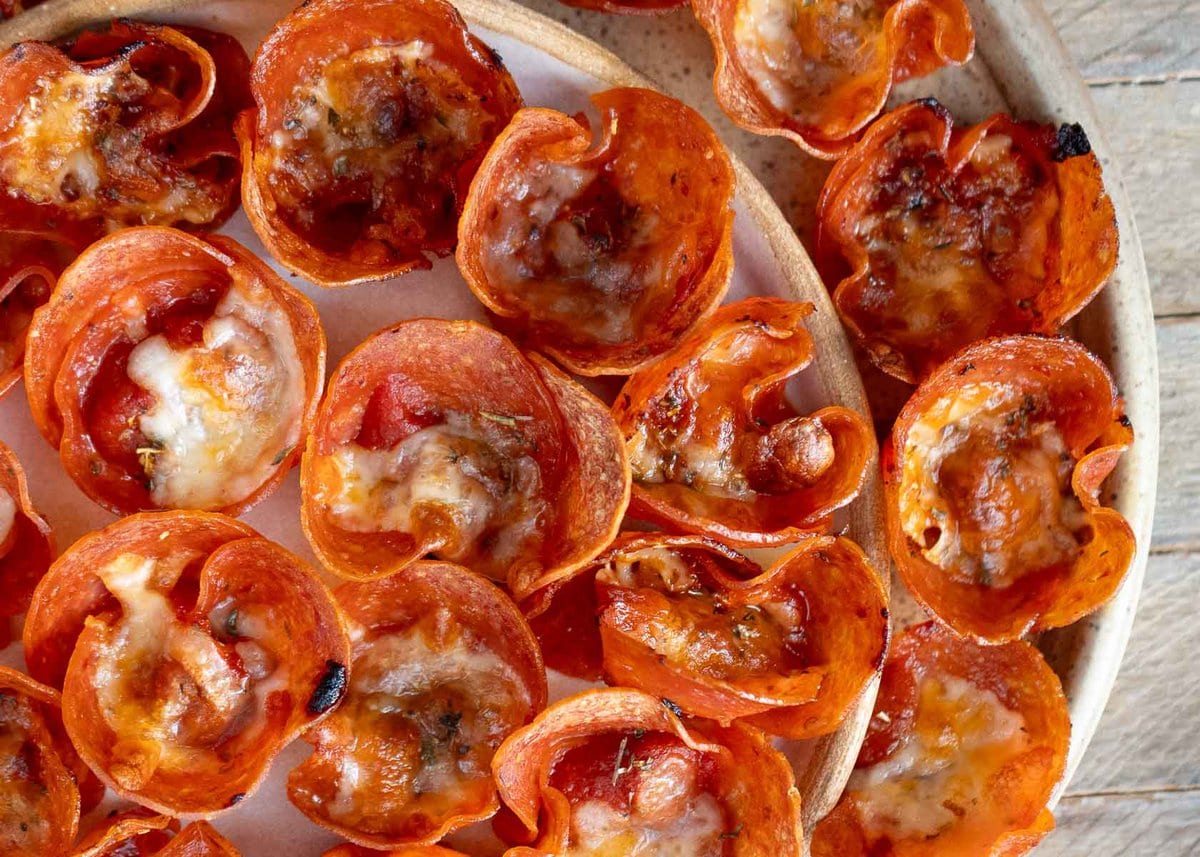 horizontal image of crispy pepperoni cups filled with marinara and mozzarella on a serving platter